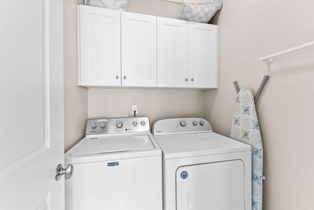 laundry area with washing machine and clothes dryer and cabinet space