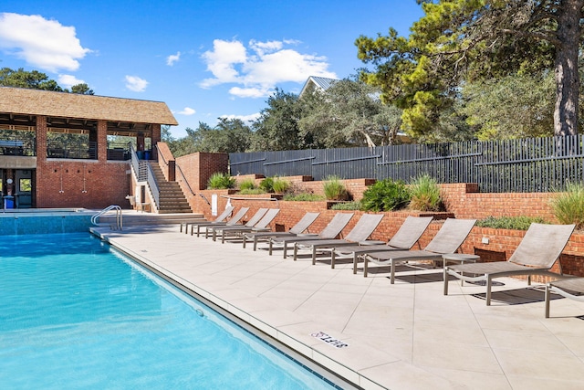 pool featuring a patio area, stairs, and fence
