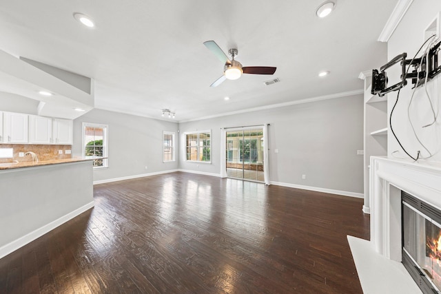 4397 Vardon Way, Niceville, FL 32578 - unfurnished living room featuring a glass covered fireplace, crown molding, ceiling fan, recessed lighting, and dark wood-style floors