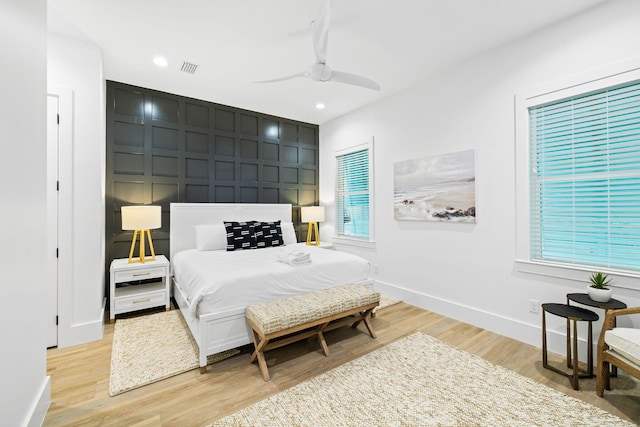 bedroom with a decorative wall, recessed lighting, baseboards, and light wood-type flooring