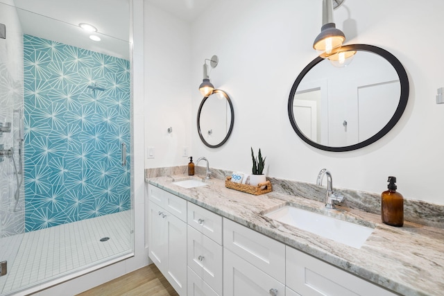 full bath featuring double vanity, tiled shower, and a sink