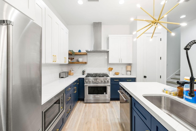 kitchen with open shelves, blue cabinets, appliances with stainless steel finishes, wall chimney range hood, and white cabinets