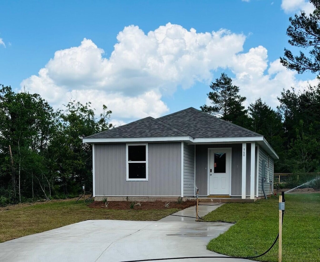 view of front of home with a shingled roof and a front lawn