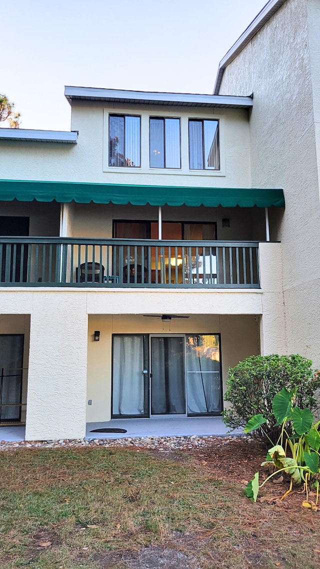 rear view of house with stucco siding and a balcony