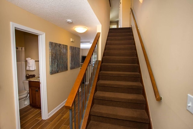 stairs with wood tiled floor, baseboards, and a textured ceiling