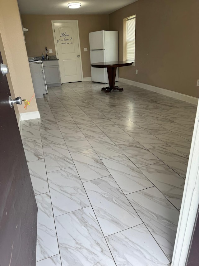 empty room featuring marble finish floor and baseboards