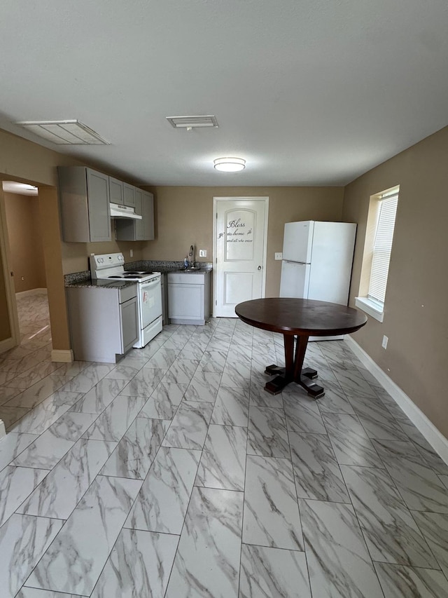 kitchen featuring visible vents, white appliances, baseboards, dark countertops, and under cabinet range hood