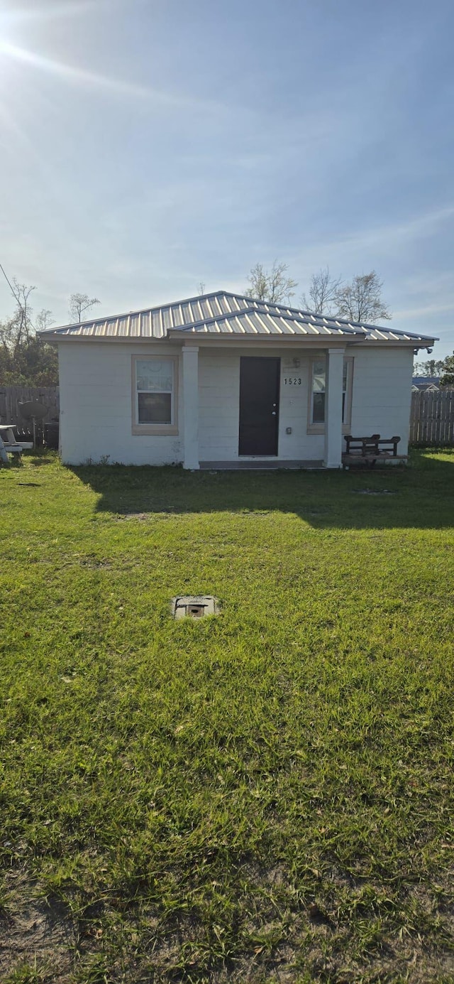 back of house featuring a lawn, metal roof, and fence
