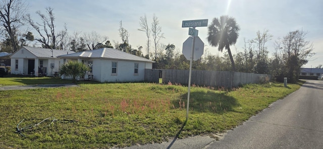 view of side of home featuring metal roof, fence, and a yard