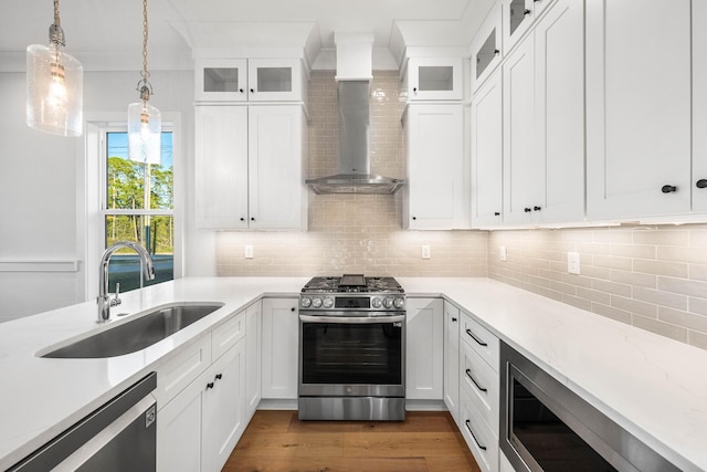 kitchen featuring decorative light fixtures, stainless steel appliances, a sink, dark wood-style floors, and wall chimney range hood