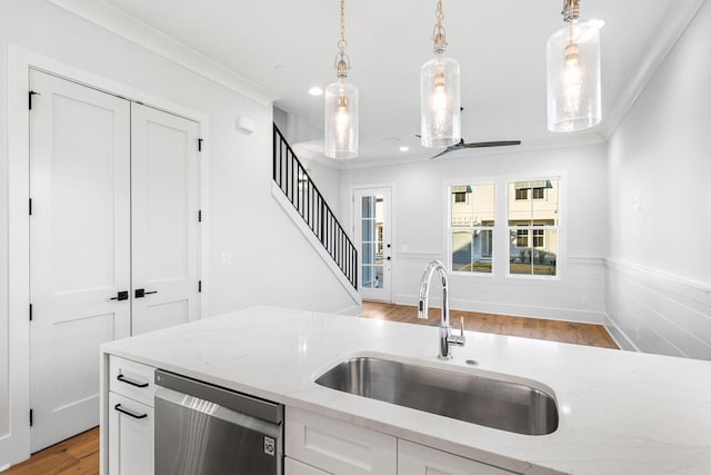 kitchen featuring hanging light fixtures, a sink, stainless steel dishwasher, and wainscoting