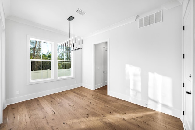 unfurnished dining area with hardwood / wood-style floors, ornamental molding, visible vents, and an inviting chandelier