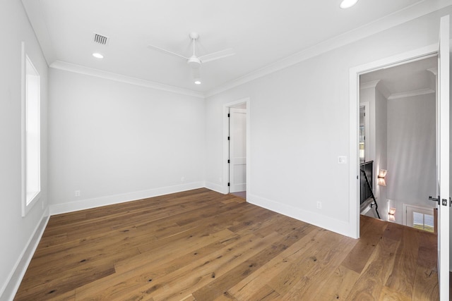 empty room with wood-type flooring, crown molding, and baseboards