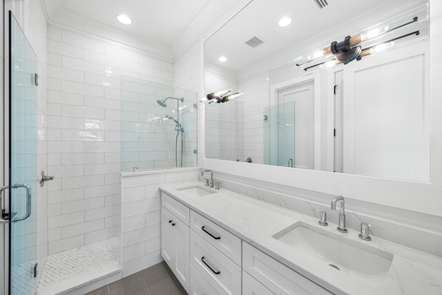 full bathroom with double vanity, a sink, a stall shower, and tile patterned floors