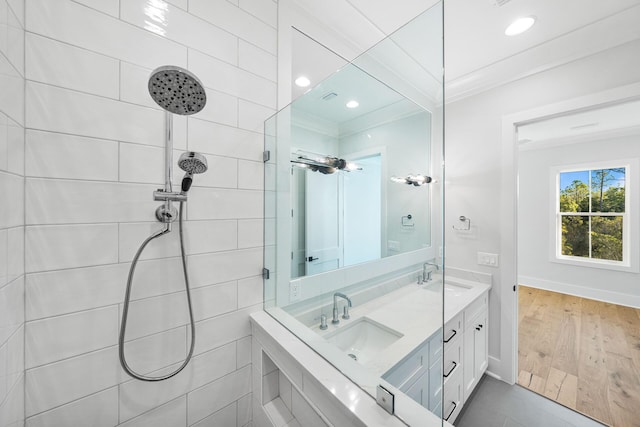 bathroom featuring a sink, ornamental molding, tiled shower, and wood finished floors
