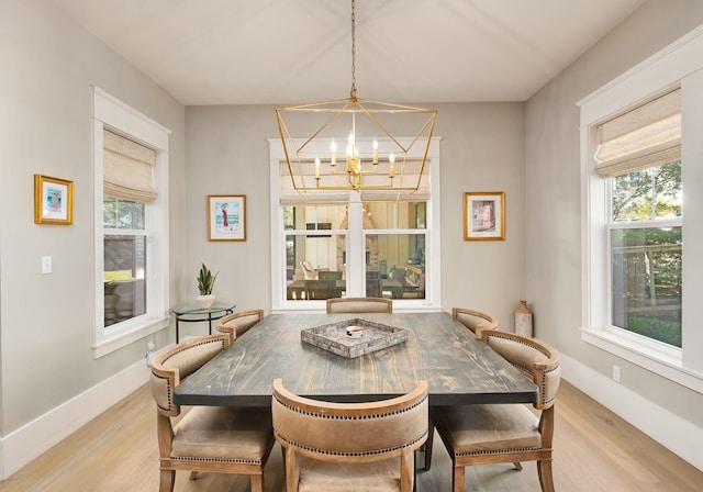 dining room with baseboards, wood finished floors, and an inviting chandelier