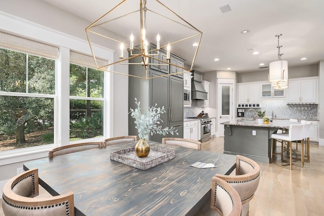 dining room with an inviting chandelier, recessed lighting, and light wood-type flooring