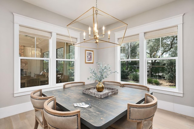 dining space with plenty of natural light, baseboards, wood finished floors, and an inviting chandelier