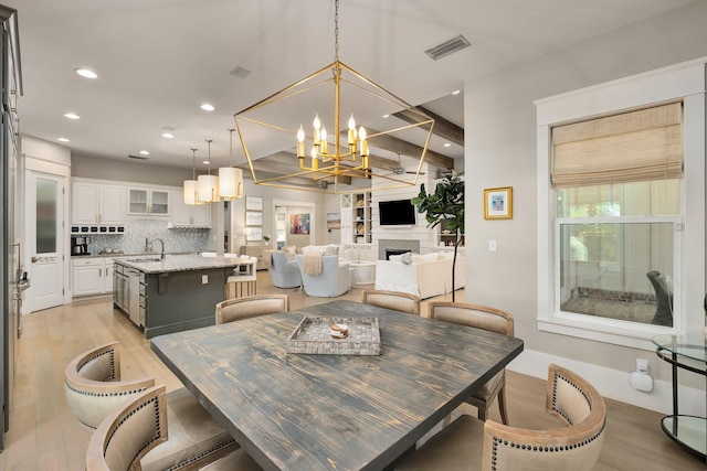 dining area with a fireplace, recessed lighting, light wood-style floors, and a notable chandelier