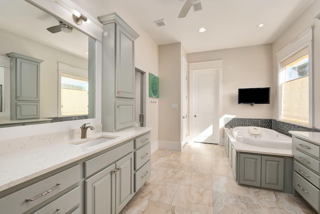 full bathroom featuring marble finish floor, vanity, a jetted tub, and ceiling fan