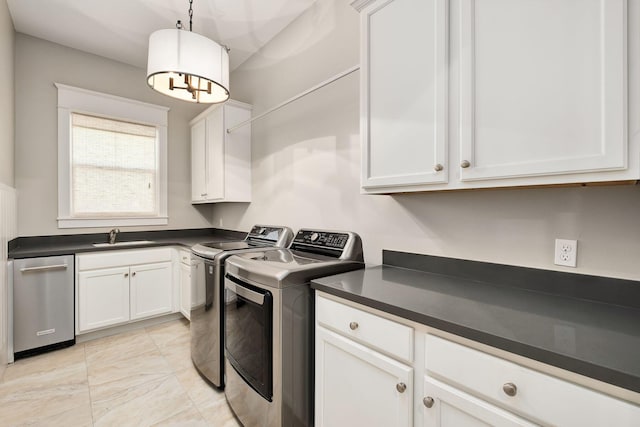 laundry room featuring separate washer and dryer, cabinet space, a sink, and a chandelier