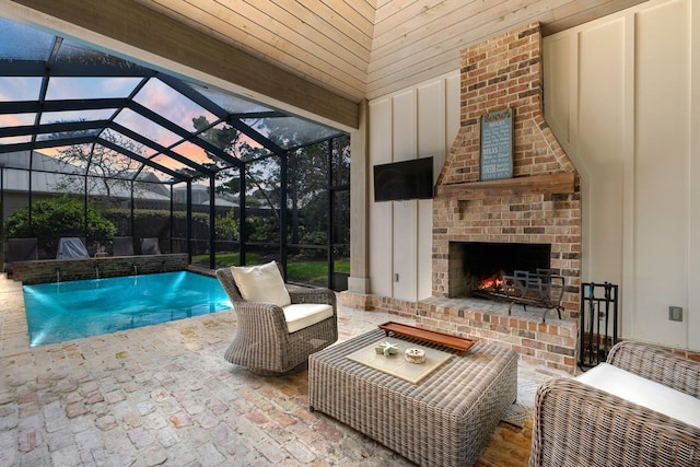 outdoor pool with an outdoor brick fireplace, a patio, and a lanai