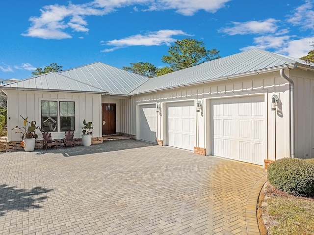 view of front of house featuring driveway, an attached garage, metal roof, and board and batten siding