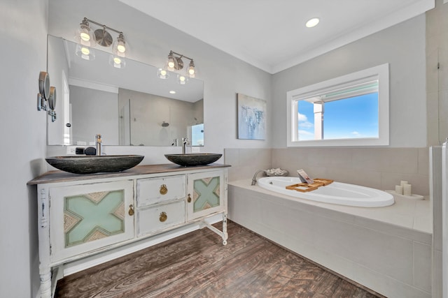 full bathroom with a garden tub, double vanity, a sink, and tiled shower