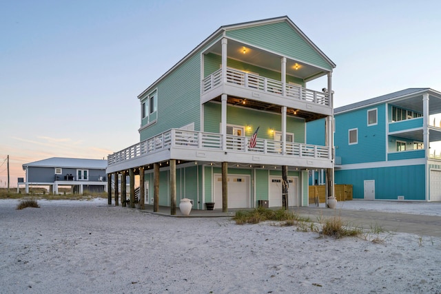 rear view of property with driveway, a balcony, and an attached garage