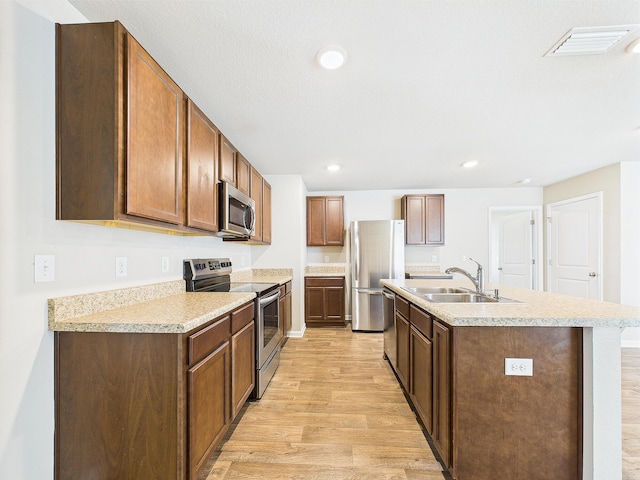 643 Earl Godwin Rd, Freeport, FL 32439 - kitchen featuring appliances with stainless steel finishes, a sink, light wood-style floors, an island with sink, and light countertops