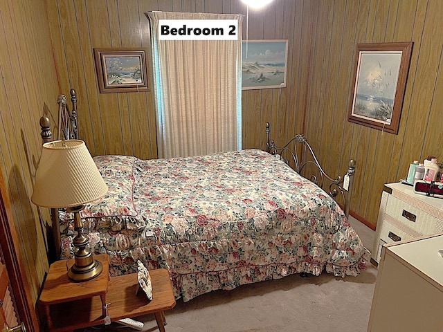 carpeted bedroom featuring wood walls
