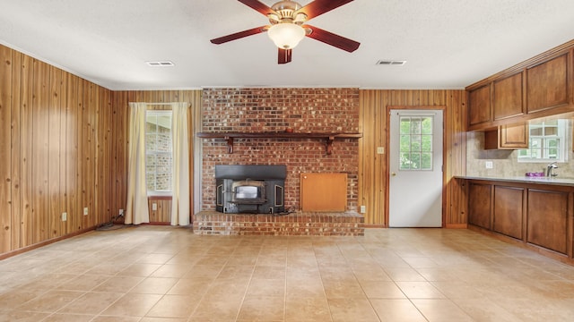 2374 County Highway 280a, Defuniak Springs, FL 32435 - unfurnished living room with wooden walls, a wood stove, ceiling fan, crown molding, and light tile patterned floors