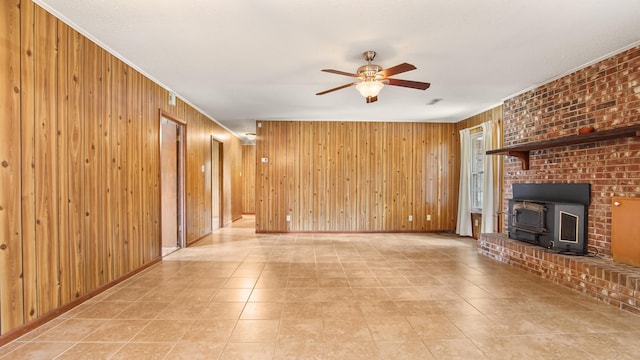 2374 County Highway 280a, Defuniak Springs, FL 32435 - unfurnished living room featuring a ceiling fan, wood walls, a wood stove, light tile patterned floors, and crown molding