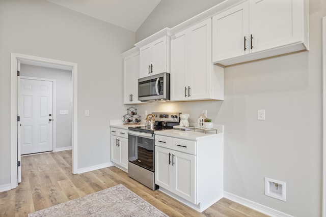 3202 Liz Ct, Crestview, FL 32539 - kitchen with appliances with stainless steel finishes, light wood finished floors, light countertops, white cabinetry, and lofted ceiling