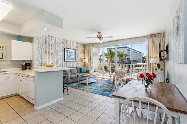 kitchen with white cabinets, a peninsula, dishwasher, a ceiling fan, and light tile patterned floors