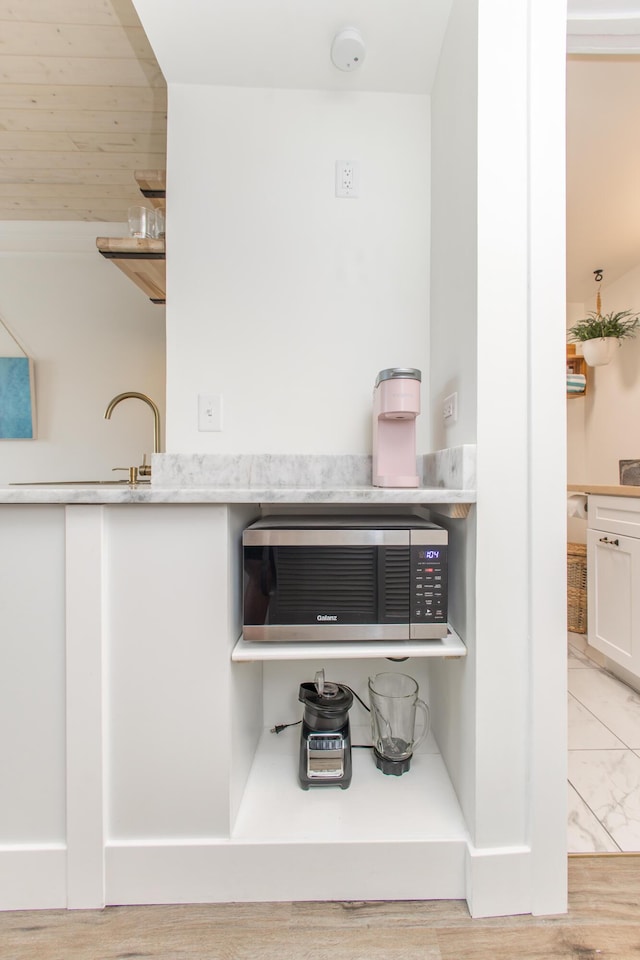 room details featuring white cabinets, light wood-style floors, a toaster, and light countertops