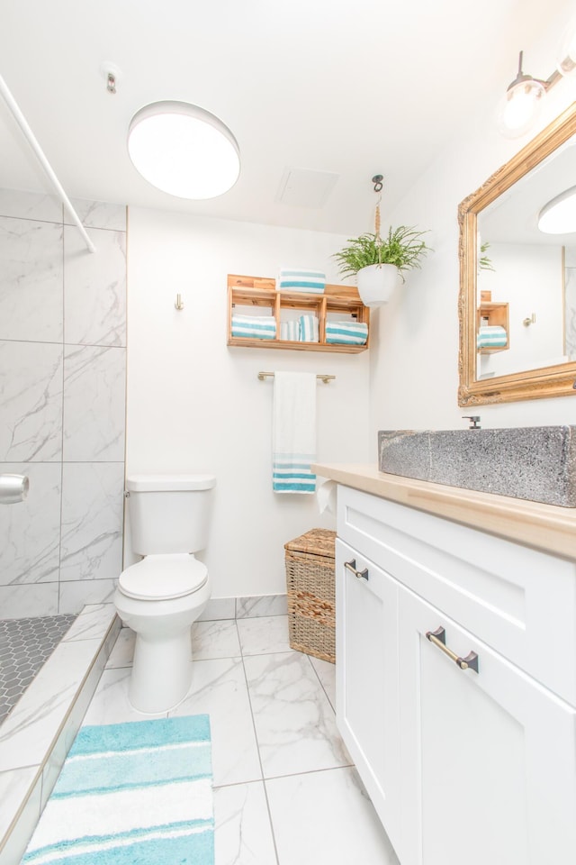 full bath featuring toilet, tiled shower, marble finish floor, and vanity