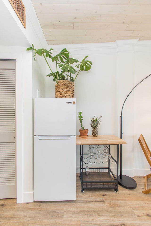 interior space with light wood-style floors, white cabinets, and freestanding refrigerator
