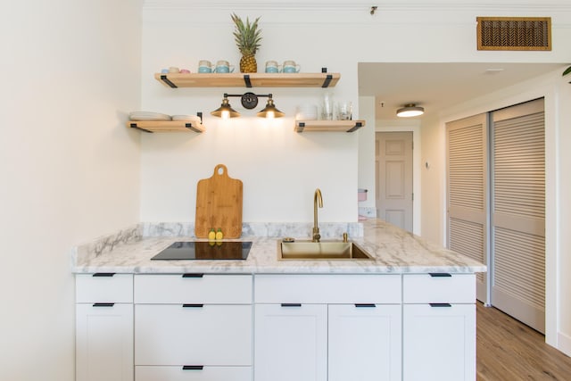 kitchen with open shelves, light stone counters, black electric stovetop, a sink, and visible vents
