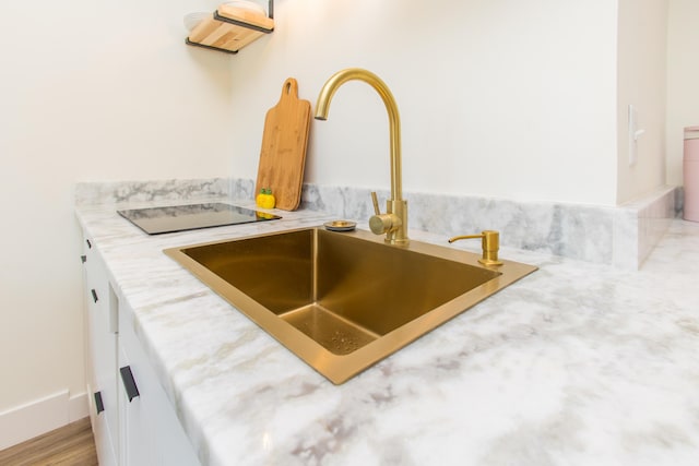 interior details with a sink, light countertops, and white cabinets