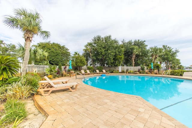 community pool with a patio and fence