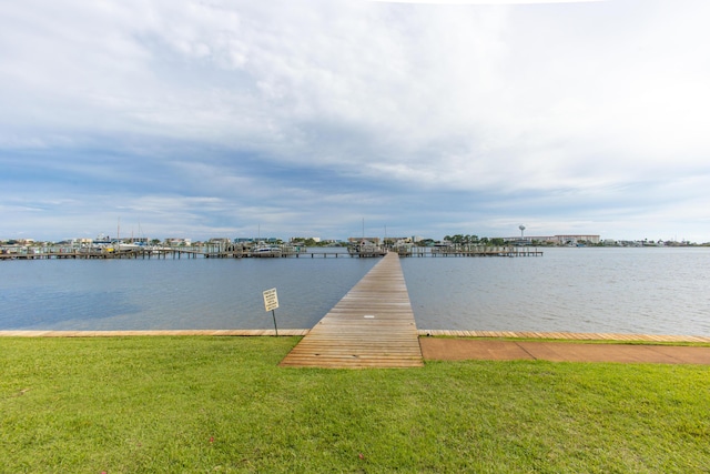 view of dock with a lawn and a water view