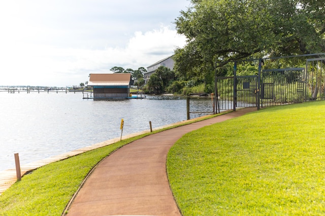 surrounding community with a lawn, fence, a boat dock, and a water view