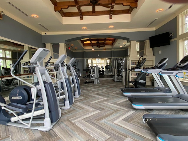 exercise room with ornate columns, arched walkways, coffered ceiling, and a wealth of natural light