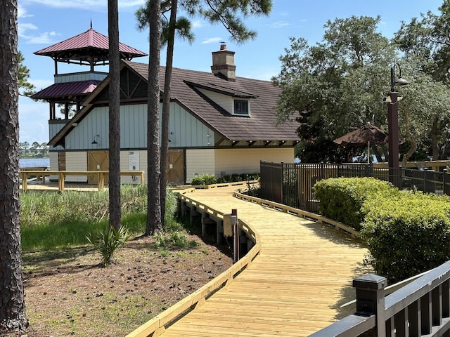 rear view of property with board and batten siding, fence, and a chimney
