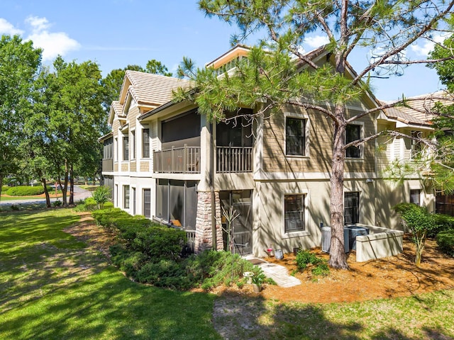 rear view of property with a lawn, central air condition unit, and stucco siding