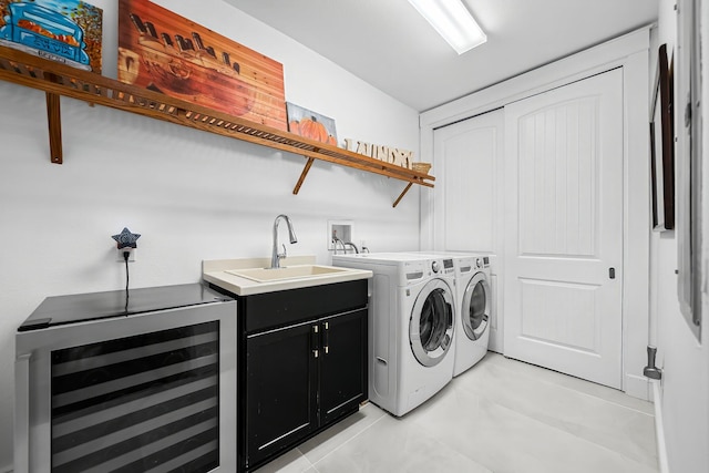 washroom featuring cabinet space, a sink, wine cooler, light tile patterned flooring, and washer and clothes dryer