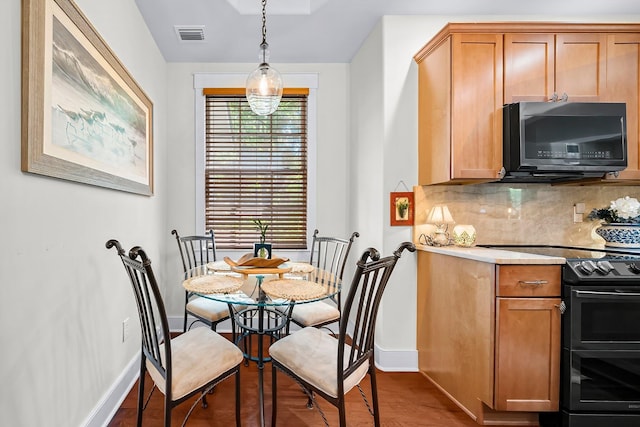 dining room with baseboards, visible vents, and wood finished floors