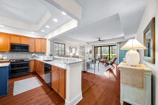 kitchen featuring dishwashing machine, stainless steel microwave, a tray ceiling, a sink, and range with electric cooktop