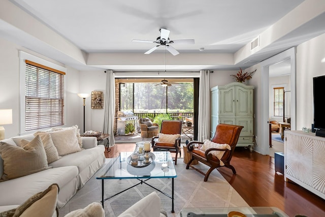 living area featuring a ceiling fan, a tray ceiling, visible vents, and plenty of natural light